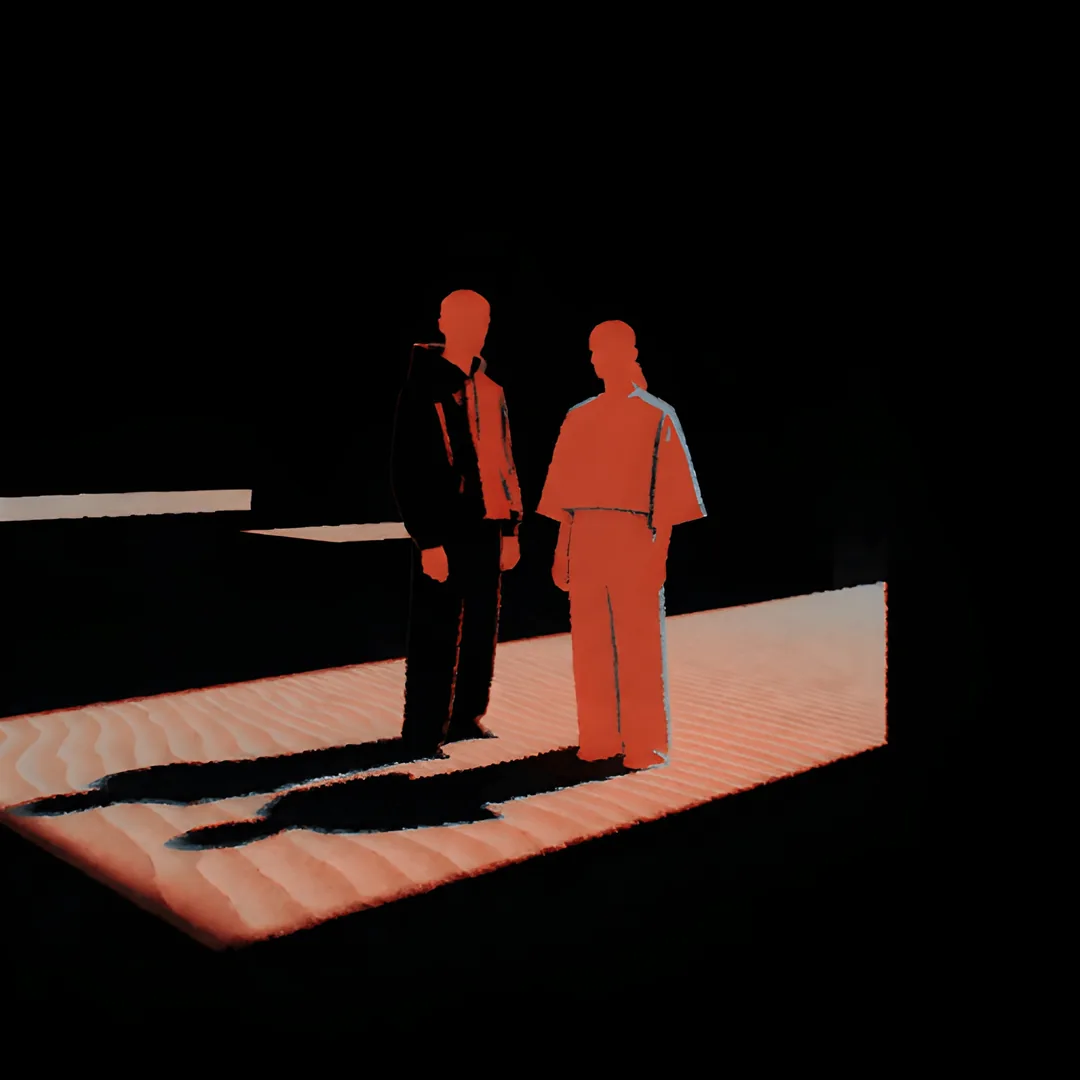 Two figures standing together on rippled sand in a single band of light, their shadows thrown long behind them.